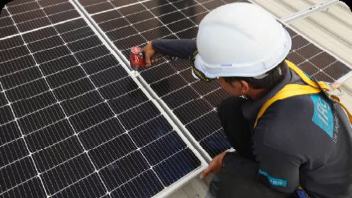 Juruteknik De Solar mengikat rangka panel solar pada bumbung logam