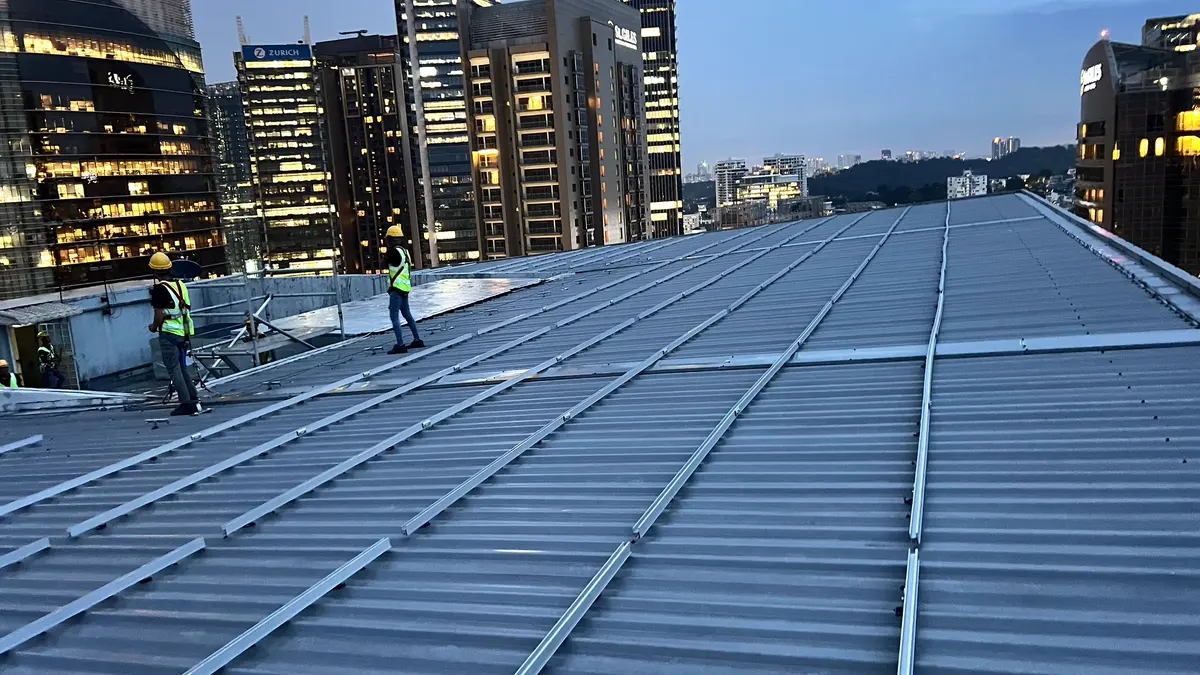 Pekerja De Solar memasang rangka solar di atas bumbung metal deck sebuah bangunan di Kuala Lumpur